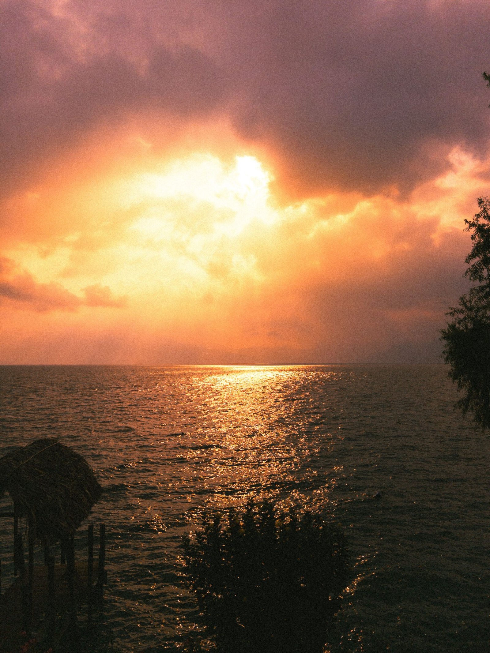 Golden sunset over Lake Atitlan with a volcanic silhouette reflected in calm water